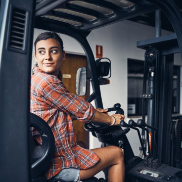 Shot of a young woman driving a forklift