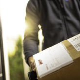 Close up of an unrecognisable courier holding cardboard box prepared for home delivery.