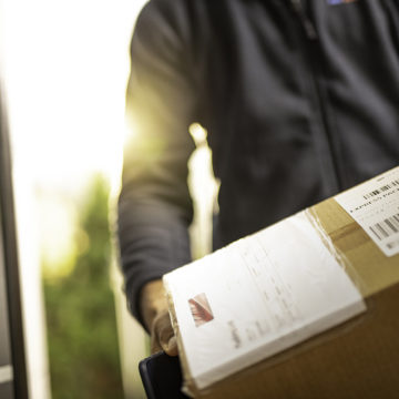 Close up of an unrecognisable courier holding cardboard box prepared for home delivery.